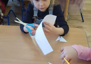 Dziewczynka wycina koronę z papieru.